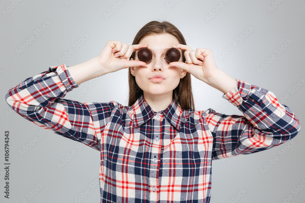 Beautiful teenage girl covered her eyes with round chocolate candies Beautiful teenage girl covered her eyes with round chocolate candies