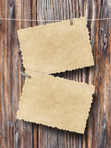Close-up of two blank brown old vintage postcard frames hanged by pegs on brown wooden boards background