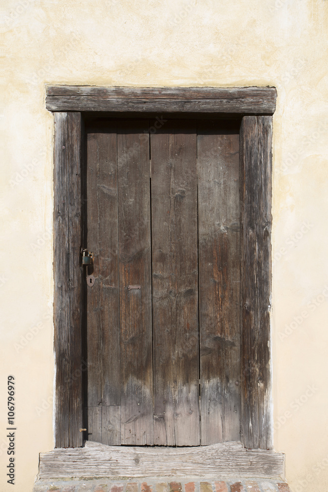 Big wooden old door. Historical house door, one timber leaf, closed brown gateway with planks and nails. Exterior country situation. Rural entry architecture element. Village foundation background. Big wooden old door. Historical house door, one timber leaf, closed brown gateway with planks and nails. Exterior country situation. Rural entry architecture element. Village foundation background.