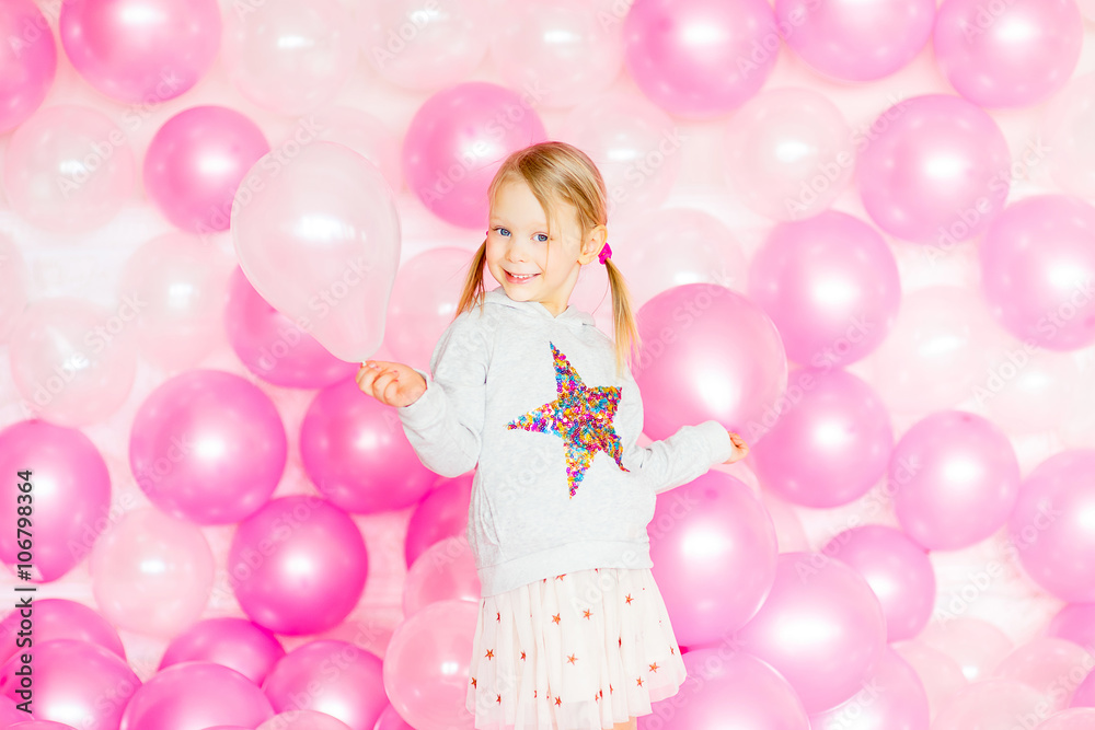 little girl playing with pink balloons