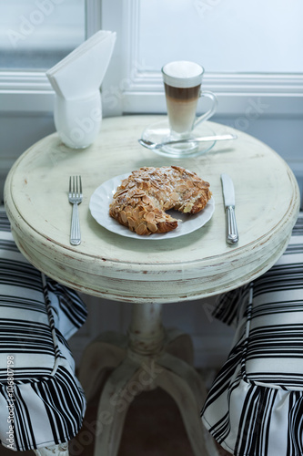 Delicious almond croissant on vintage white table with hot coffe