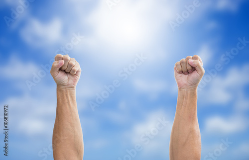 Male fist on blue sky background