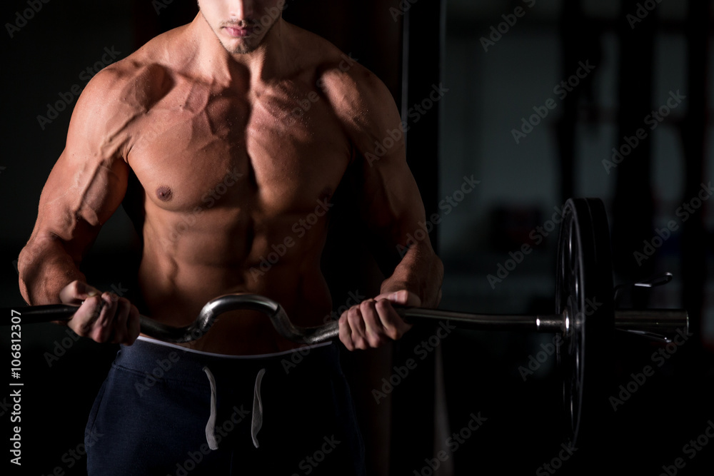 Muscular man lifting a barbell in gym Muscular man lifting a barbell in gym