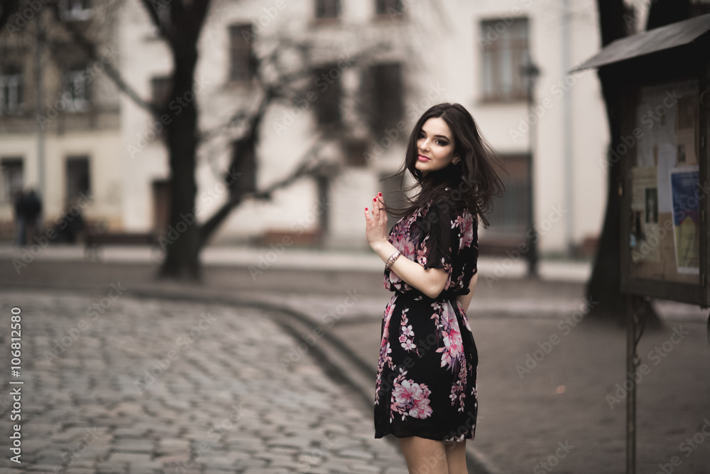 Fototapeta premium Beautiful brunette young woman posing on the street in old city