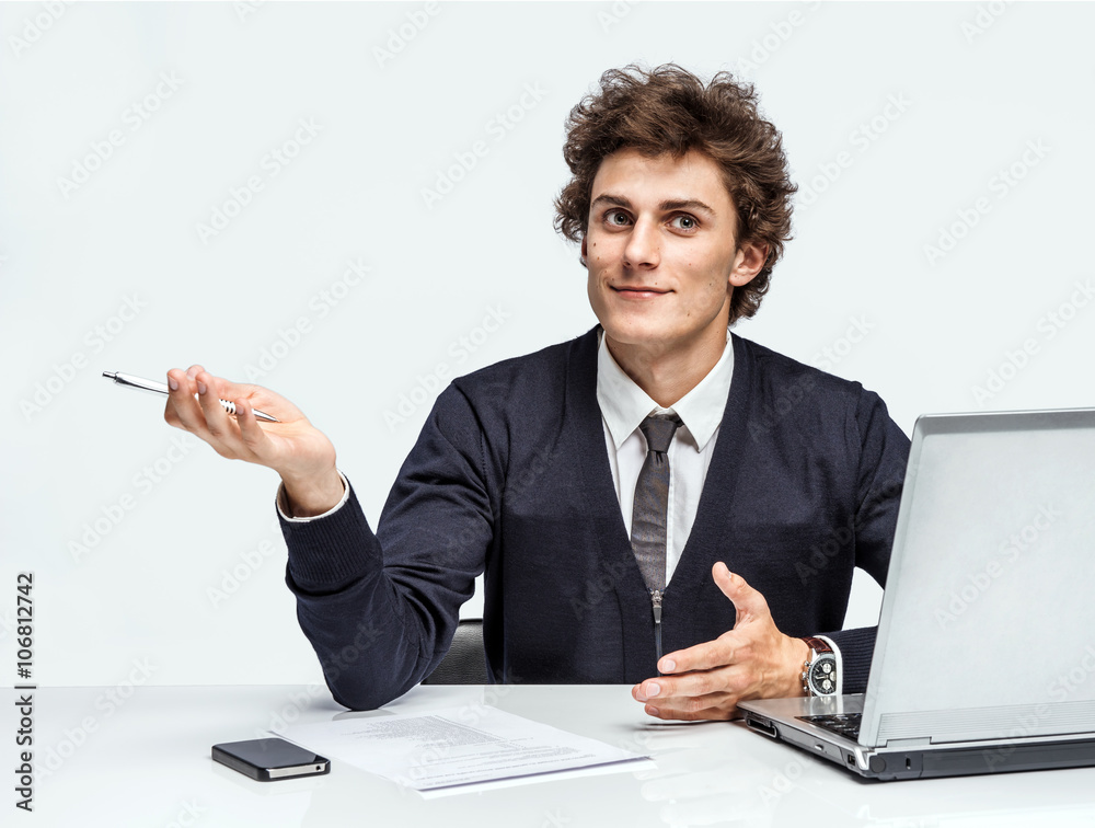 Young student thinking while writing notes. Man at the workplace working with computer on gray background. Young student thinking while writing notes. Man at the workplace working with computer on gray background.