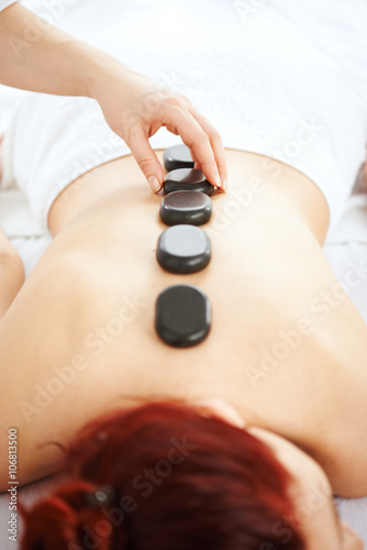 Woman having hot stones on her back in spa salon