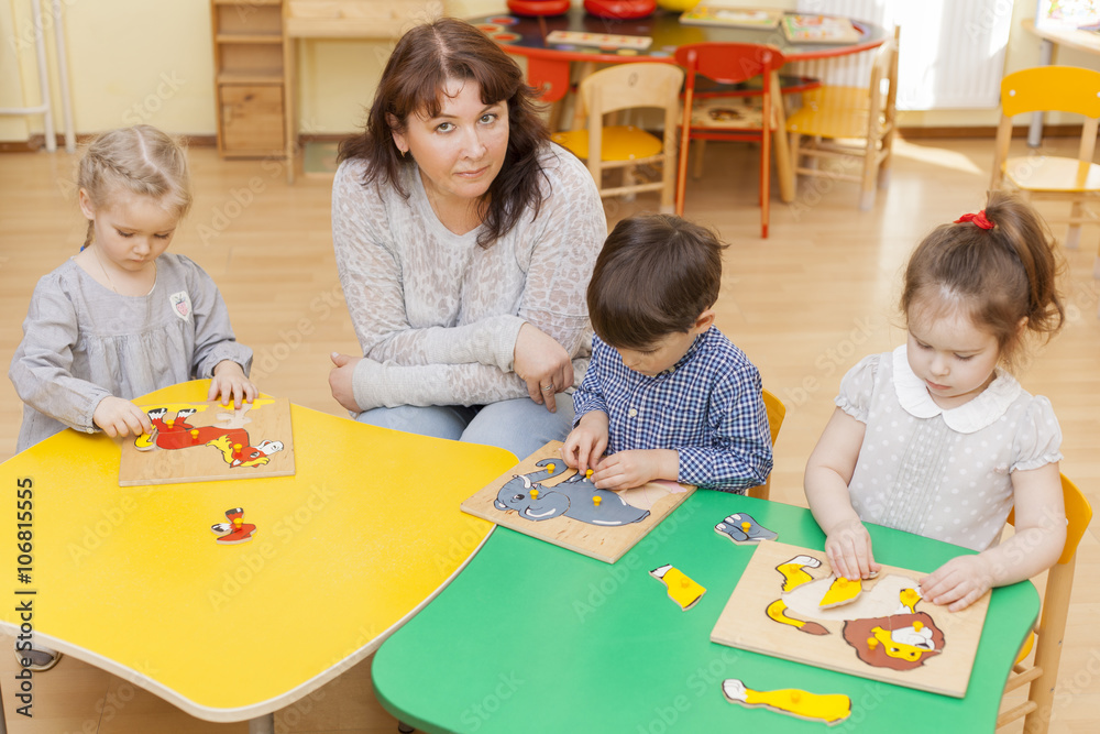 Fototapeta premium The teacher of preschool children with three students collect pu