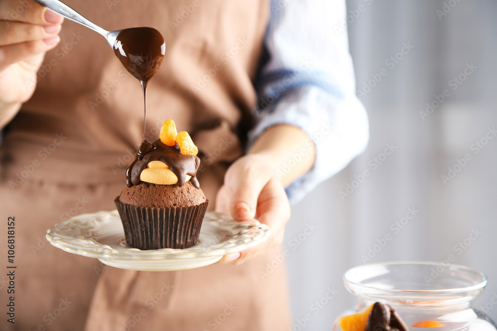 Φωτογραφία Female baker decorating tasty cupcake with slice of mandarin and chocolate on th