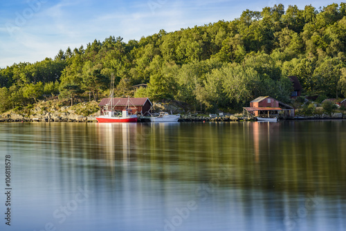 long time exposure of fishing boats and red rorbu fishing huts in fjord landscape of Norway, Europe 