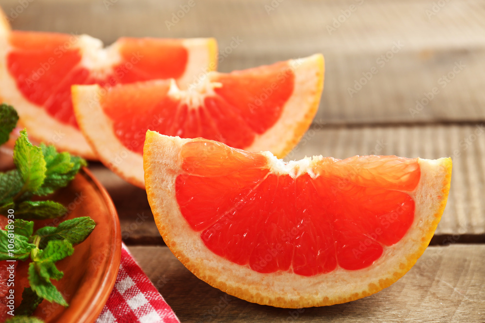 Juicy pieces of grapefruit with fresh mint on wooden table, close up Juicy pieces of grapefruit with fresh mint on wooden table, close up