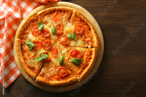 Sliced Margherita pizza on wooden background