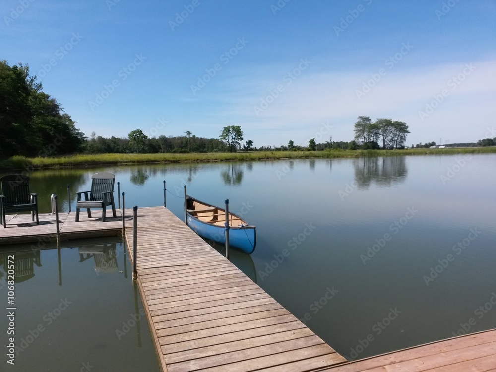 A small rowboat by a dock on a lake.