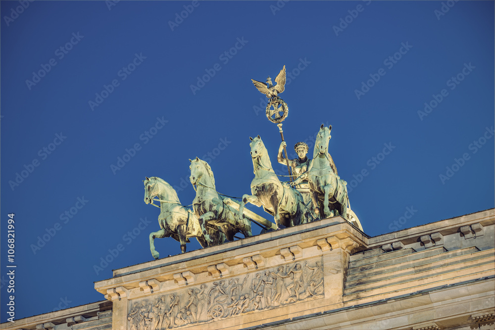 the bronze sculpture Quadriga on top of the Brandenburg Gate (Brandenburger Tor) at evening, Berlin, Germany, Europe, vintage filtered style
