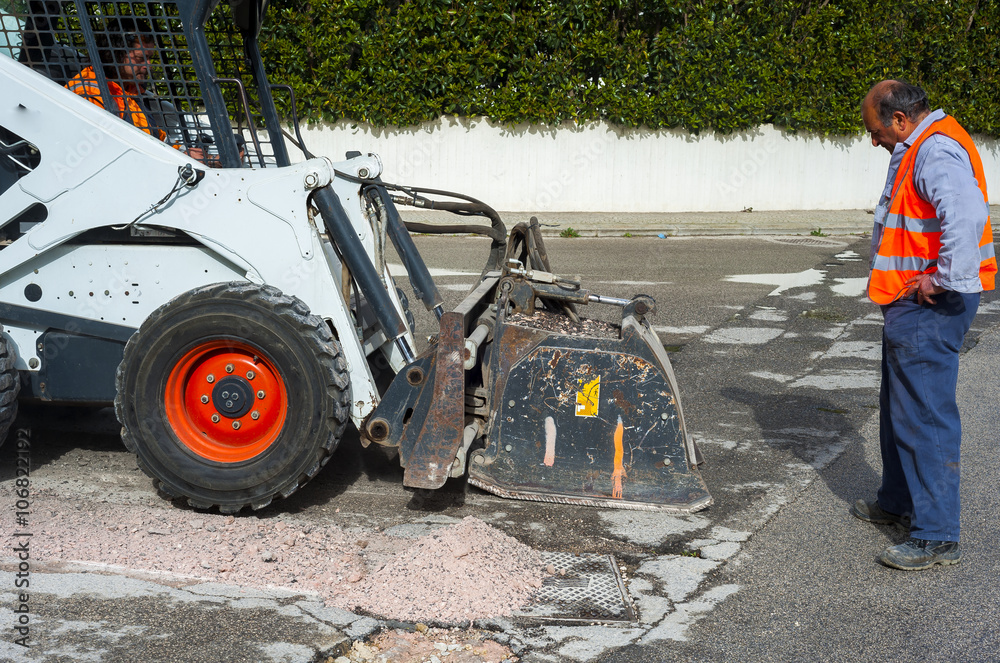 Worker checks the progress of the Milling of asphalt for road reconstruction accessory for skid steer