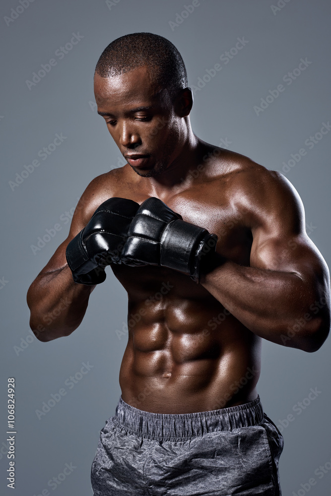 Muscular lean man boxer in black boxing punching gloves