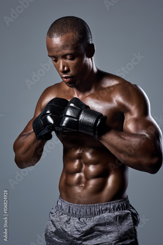 Muscular lean man boxer in black boxing punching gloves © Daxiao Productions