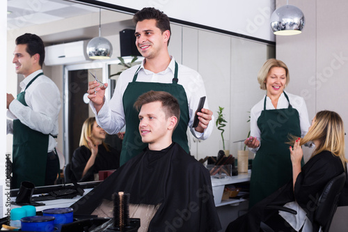 Hairdresser cutting hair of teenage