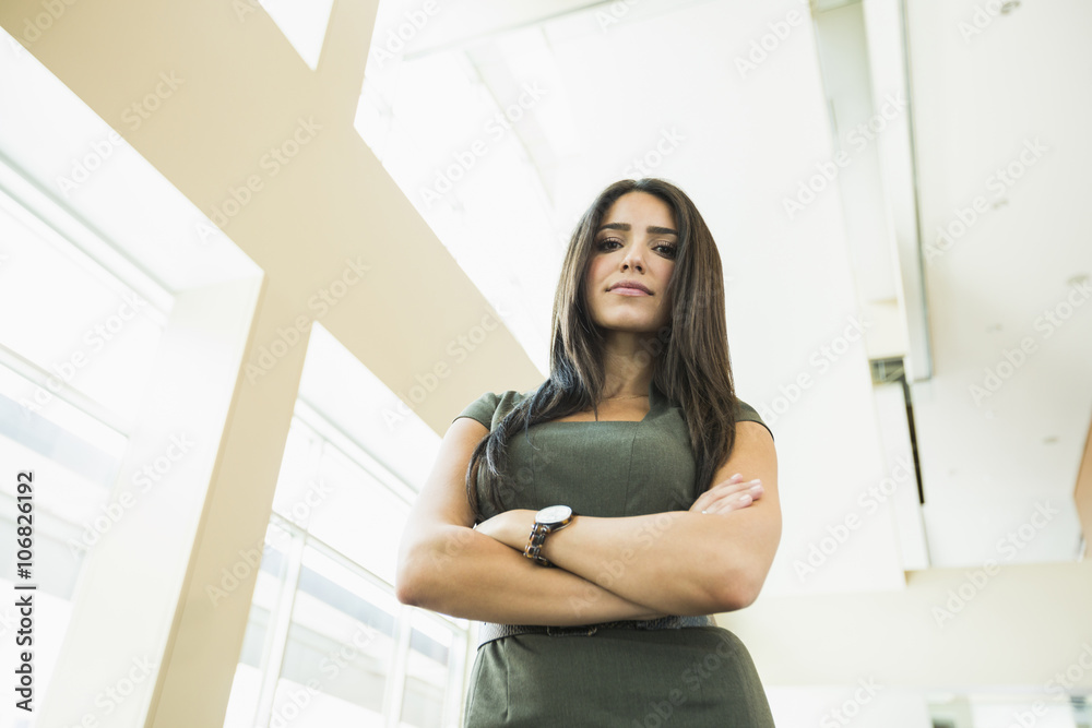 Low angle view of Hispanic businesswoman standing in office Low angle view of Hispanic businesswoman standing in office