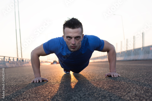 Handsome male runner doing push-ups on stairs in urban setting, © Myvisuals