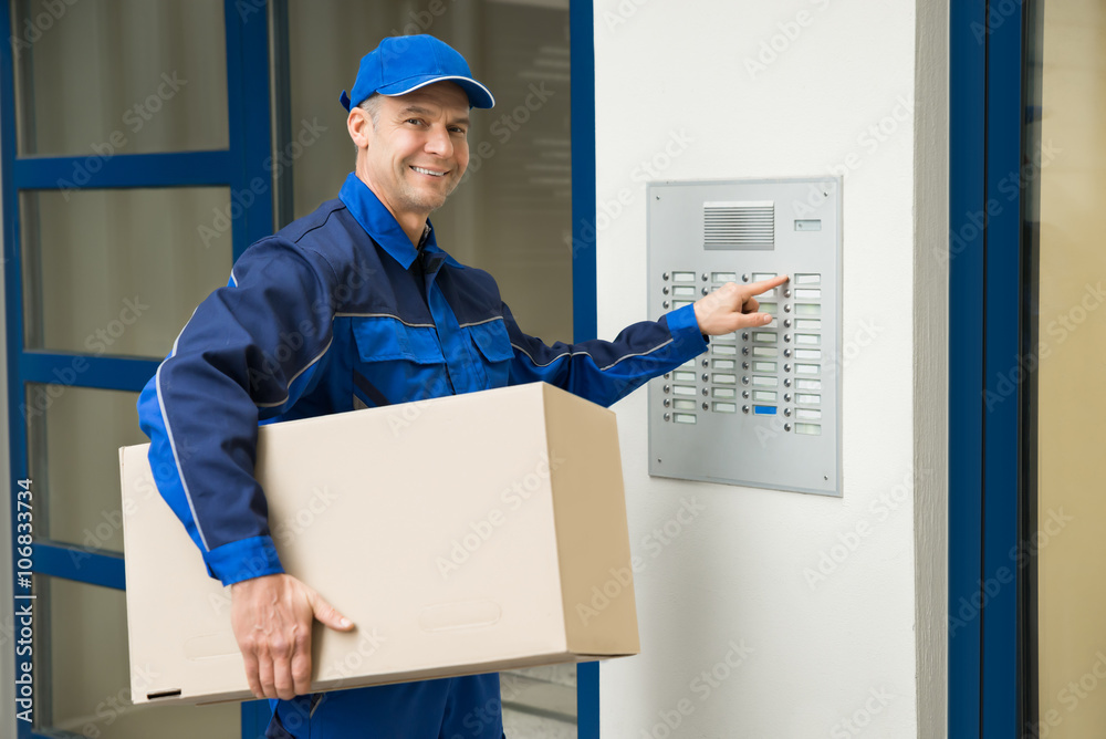 Delivery Man Pressing Button Of Intercom To Enter Building Delivery Man Pressing Button Of Intercom To Enter Building