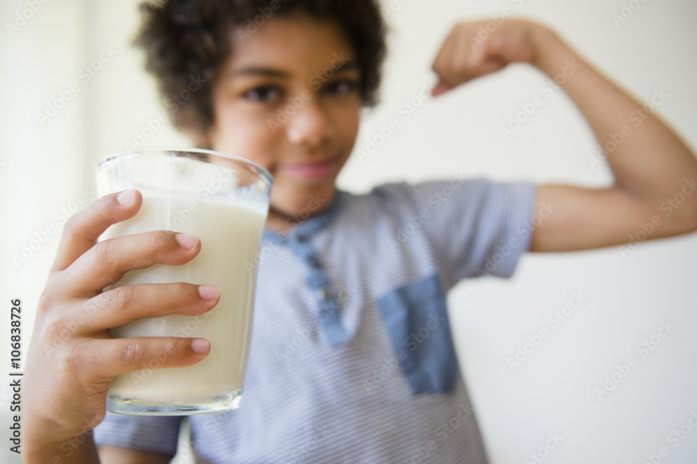 Mixed race boy flexing his muscle and drinking glass of milk Mixed race boy flexing his muscle and drinking glass of milk