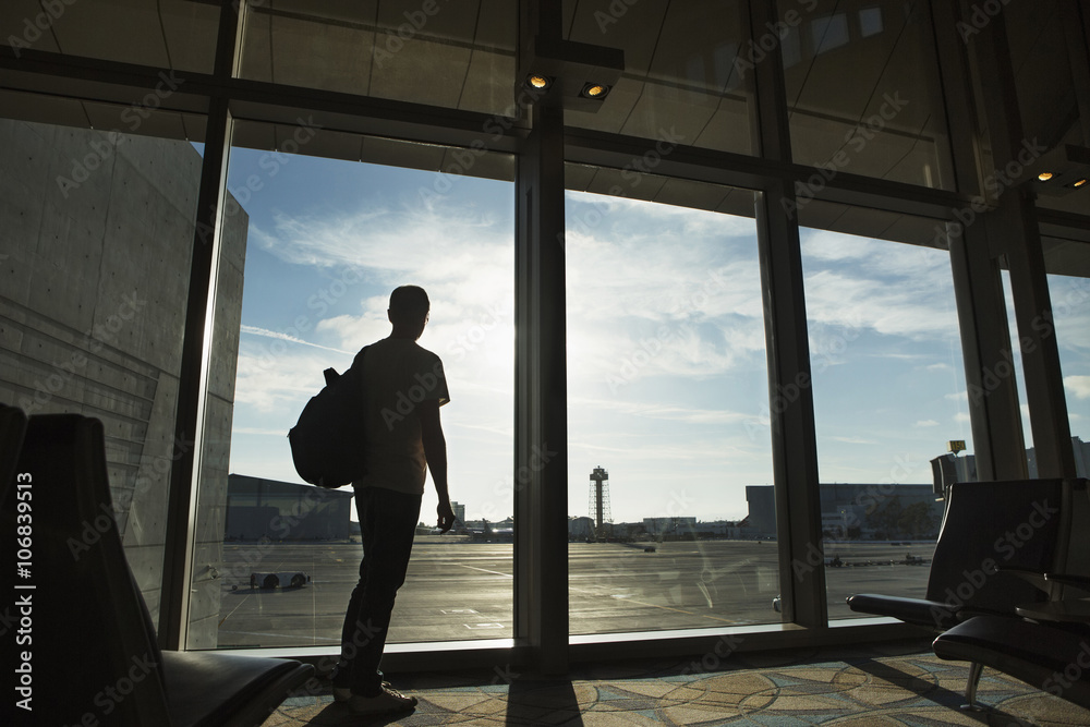 Silhouette of man looking out airport window Silhouette of man looking out airport window