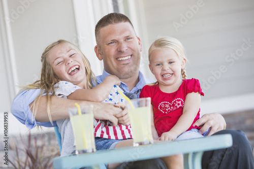 Caucasian father and daughters laughing on porch photo