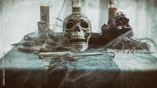 Voodoo Mist Skull Ritual. Voodoo related objects on a table including a skull, a knife and candles. Smoke or mist. photo