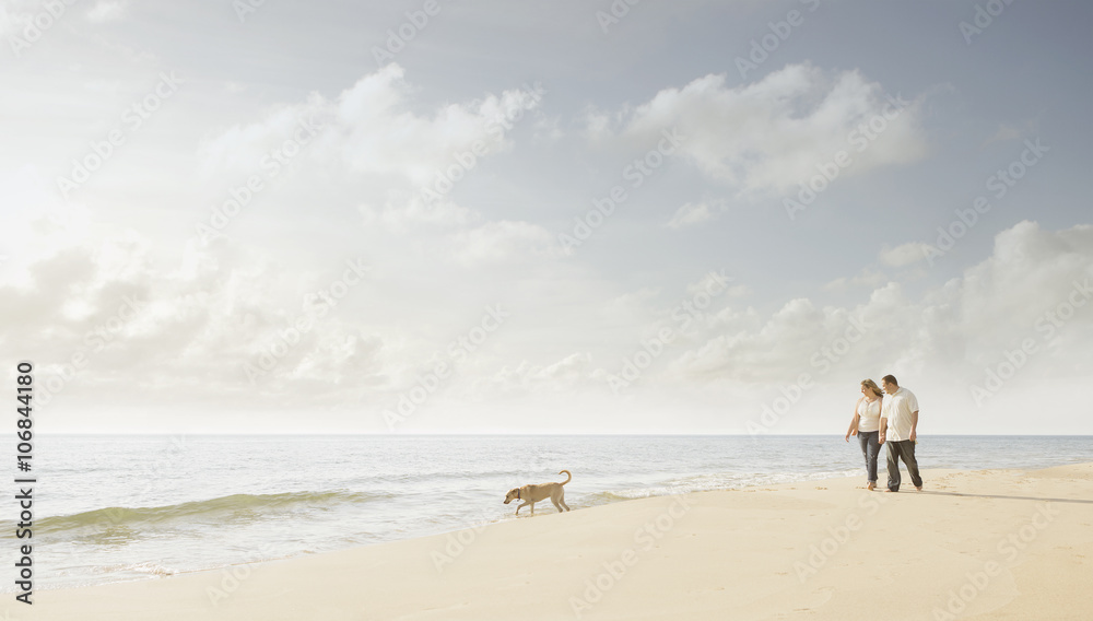 Caucasian couple walking dog on beach Caucasian couple walking dog on beach