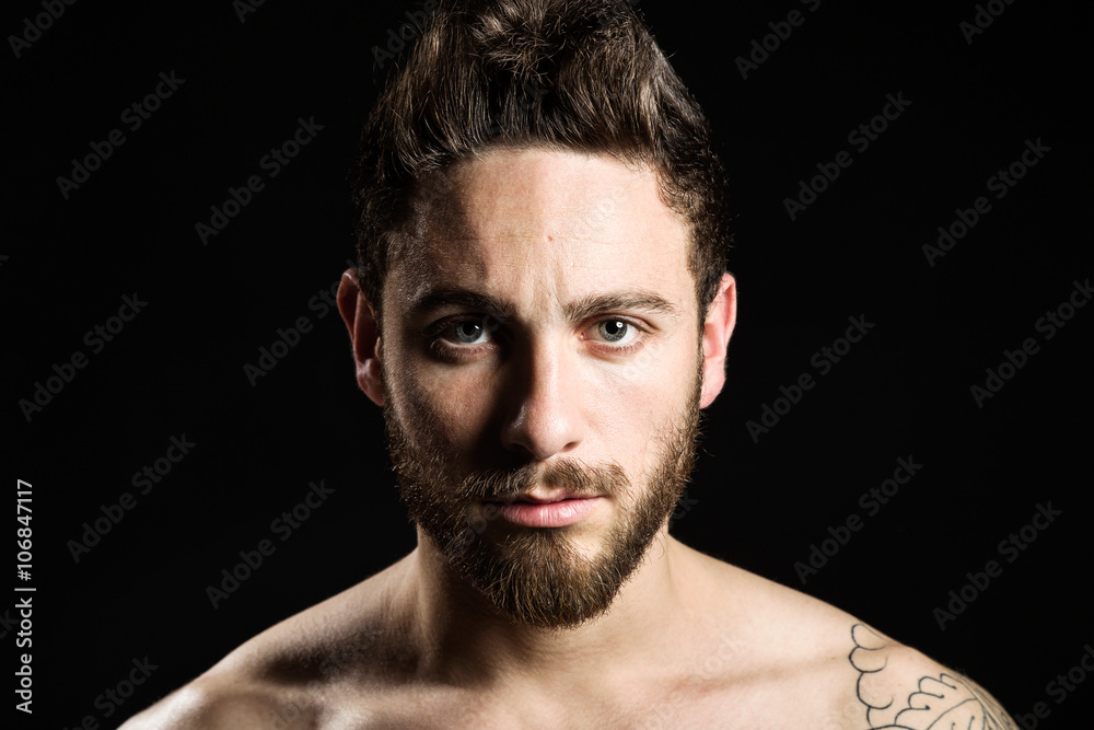 Handsome young man with tattoos posing. Isolated on black.