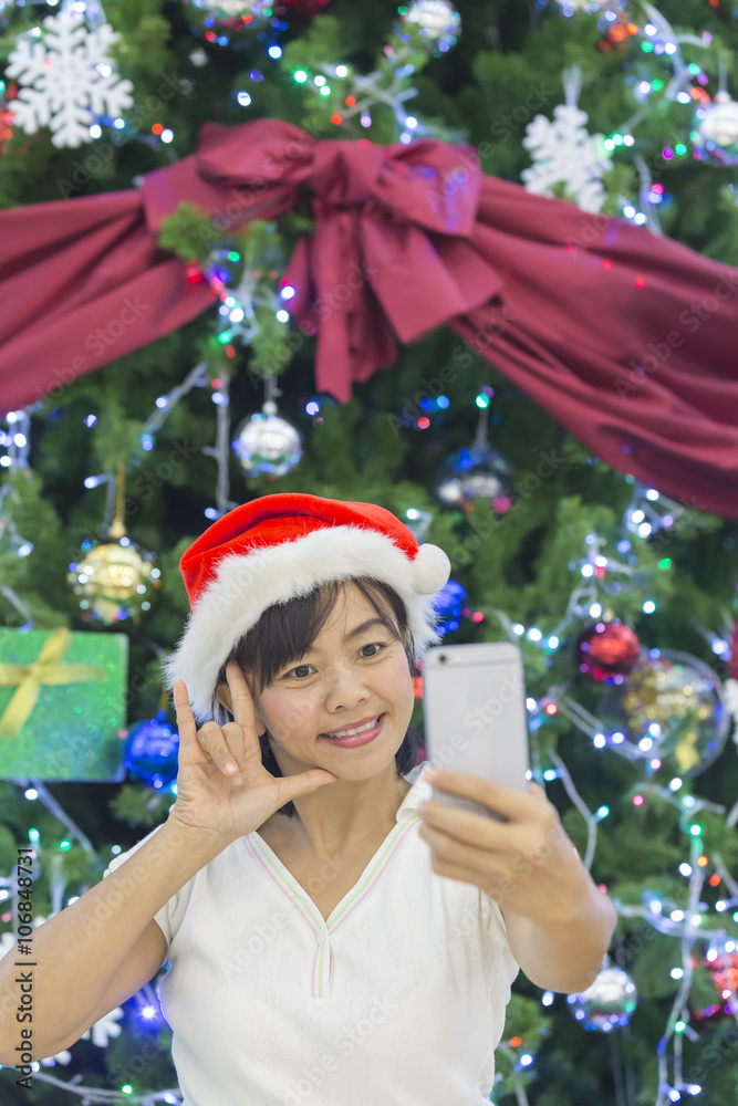 Woman in santa hat taking picture by smatrphone