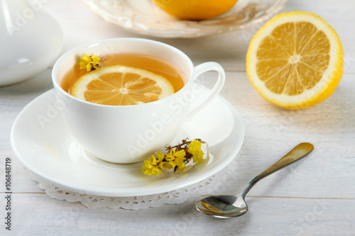 a Cup of fragrant green tea and an iron spoon with lemon on wooden background