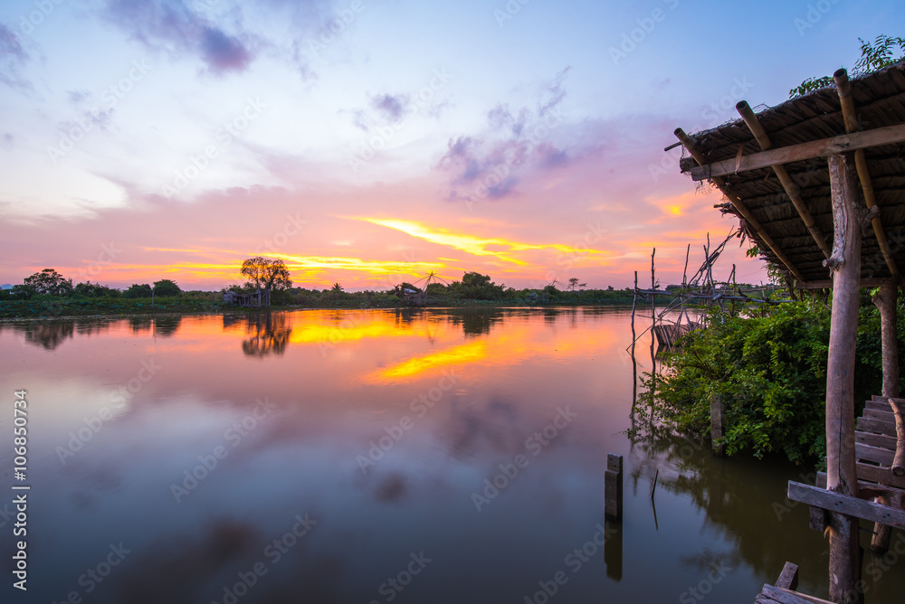 Part of shack near river in sunset.