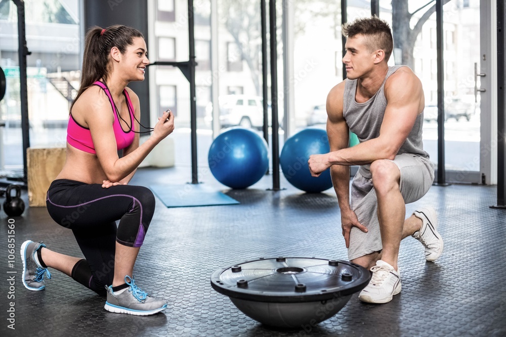 Obraz premium Athletic man working out helped by trainer woman