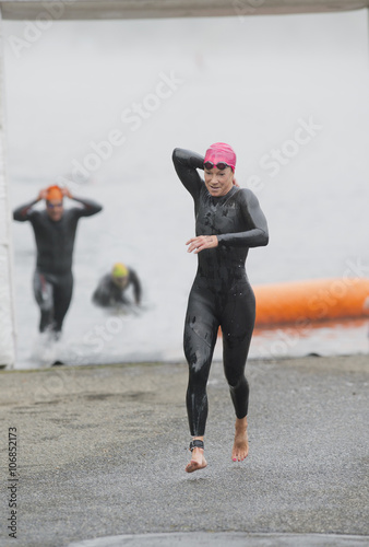 Athlete in triathlon removing wet suit after swimming photo