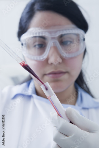 Hispanic scientist pipetting blood sample