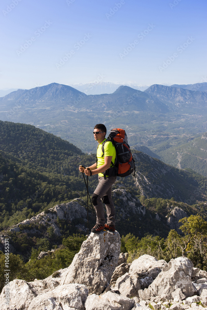 Young man with backpack on a mountain top on a sunny day.