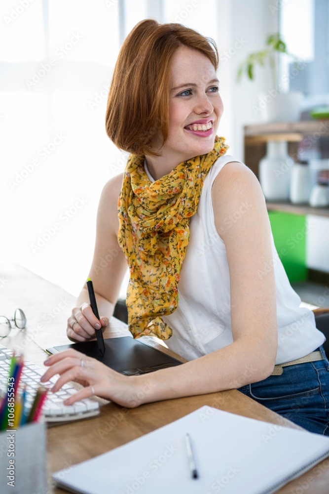 smiling hipster businesswoman writing on a digital drawing tablet in her office