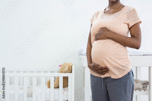Foto Pregnant woman standing near cradle