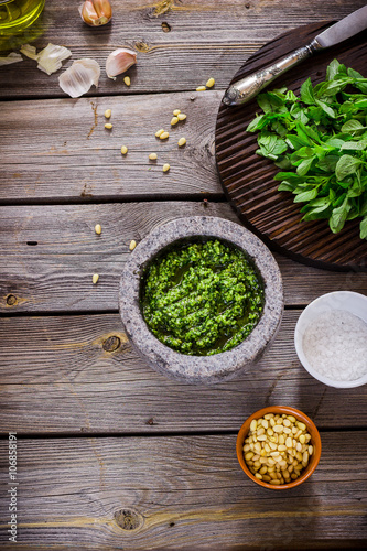 Pesto and ingredients on wooden table.