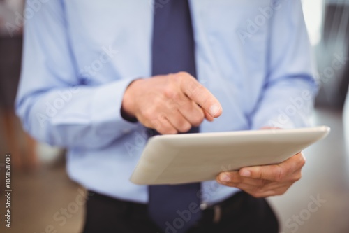 Mid section of businessman using digital tablet