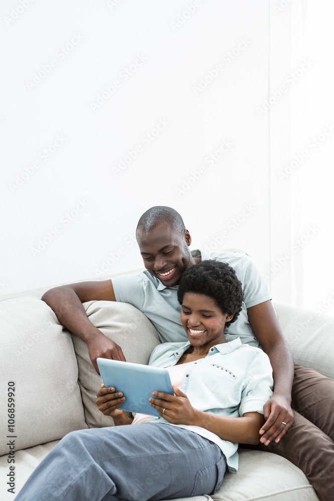 Pregnant couple using digital tablet on sofa Pregnant couple using digital tablet on sofa
