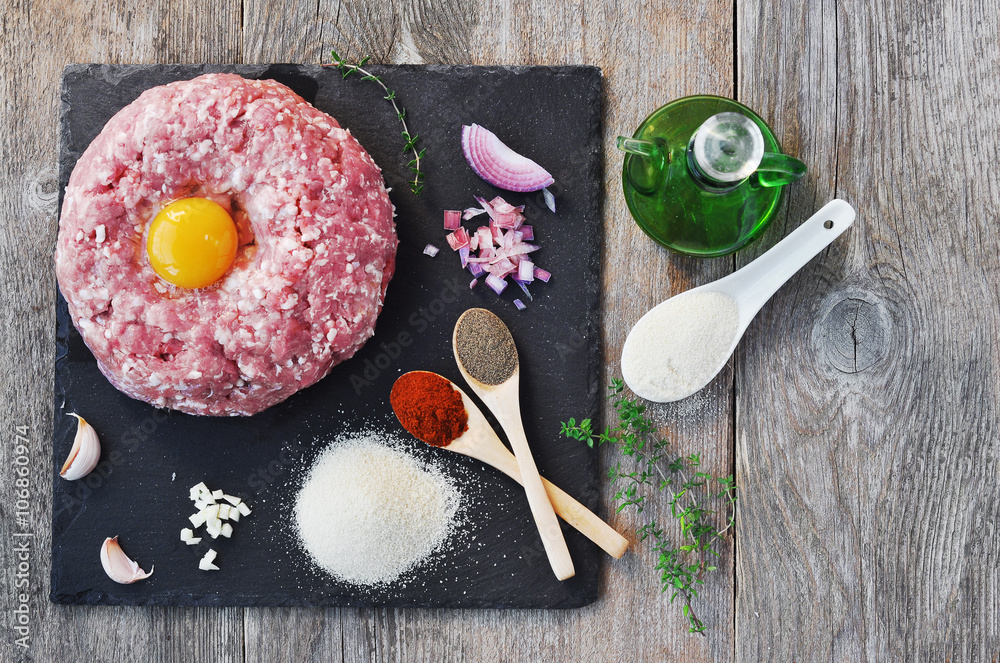 Minced meat with spices, egg and bread crumbs on a stone surface. Minced meat with spices, egg and bread crumbs on a stone surface.