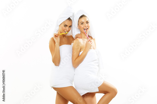 Two girls brush their teeth after shower