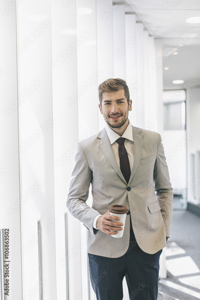 Caucasian businessman drinking coffee in office corridor Caucasian businessman drinking coffee in office corridor