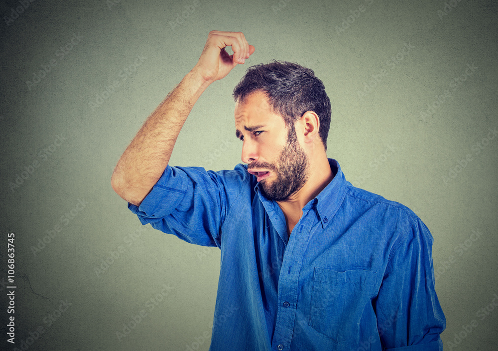 young man, smelling, sniffing his armpit, something stinks, very bad, foul odor young man, smelling, sniffing his armpit, something stinks, very bad, foul odor