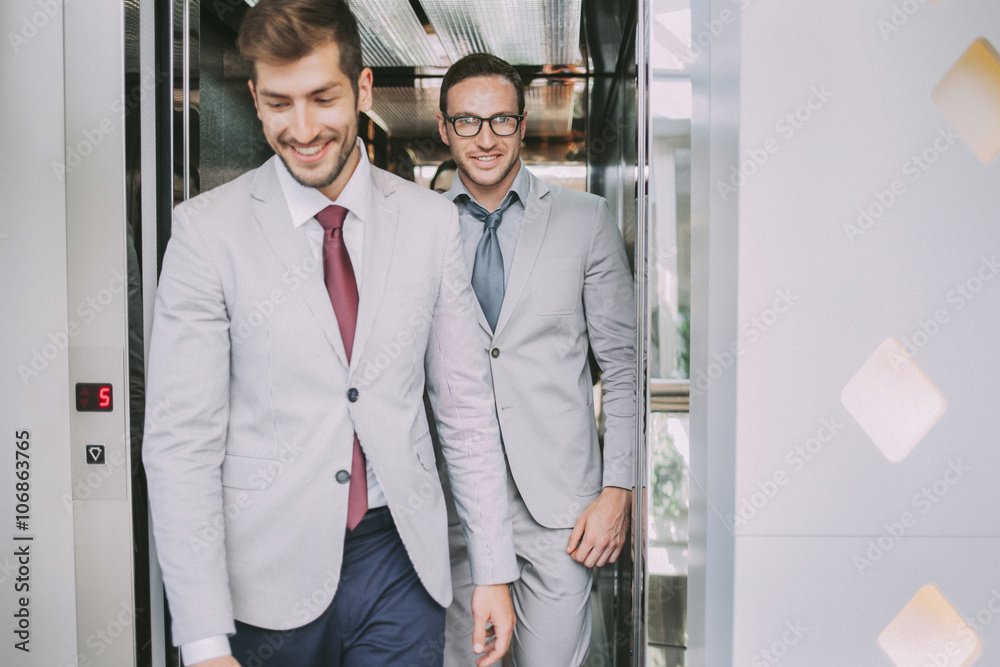 Caucasian businessmen walking out of elevator Caucasian businessmen walking out of elevator