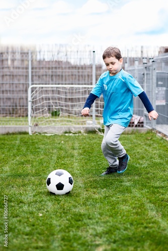 7 years boy kicking ball in the garden. © Daniel Jędzura
