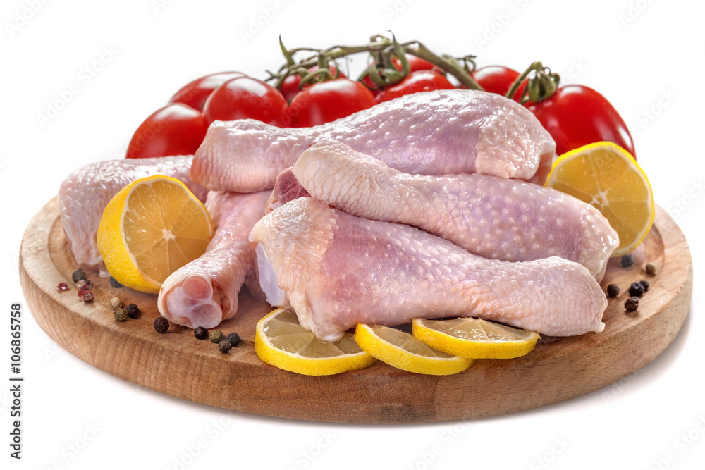 .Fresh chicken legs with tomatoes, lemon and spices, on a white background .Fresh chicken legs with tomatoes, lemon and spices, on a white background