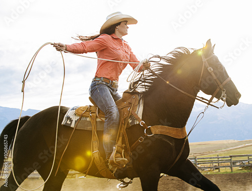 Caucasian woman on horse throwing lasso at rodeo photo